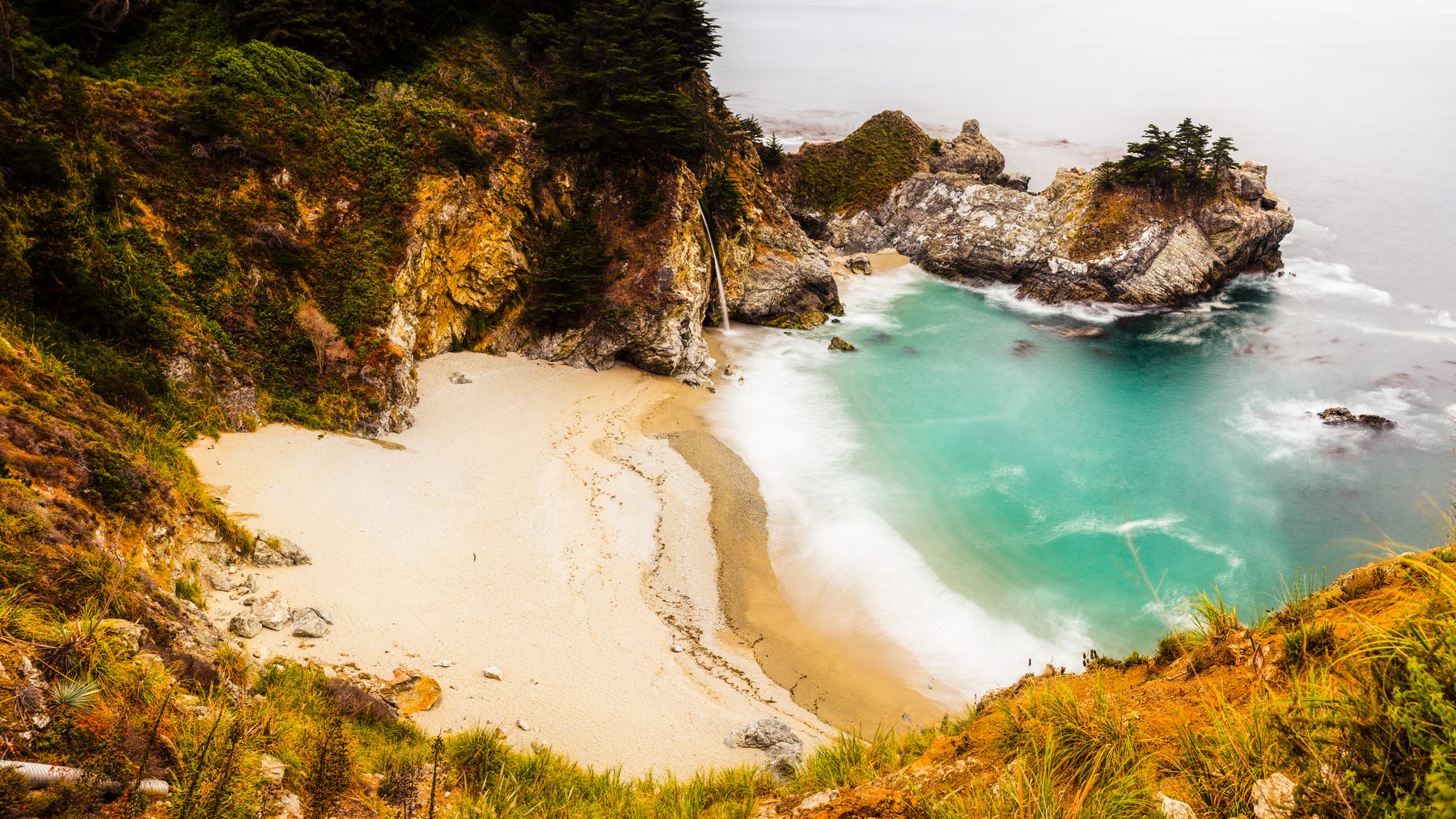 The turquoise water and pale sand of McWay Cove seen from the cliff above