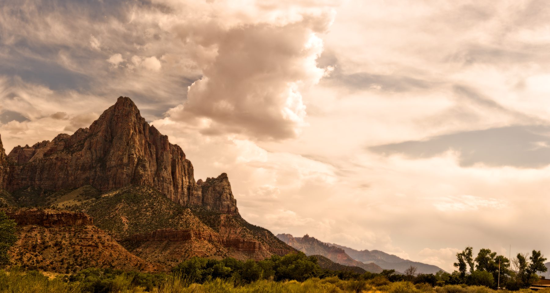 The Watchman peak lit warm against a sky of towering clouds