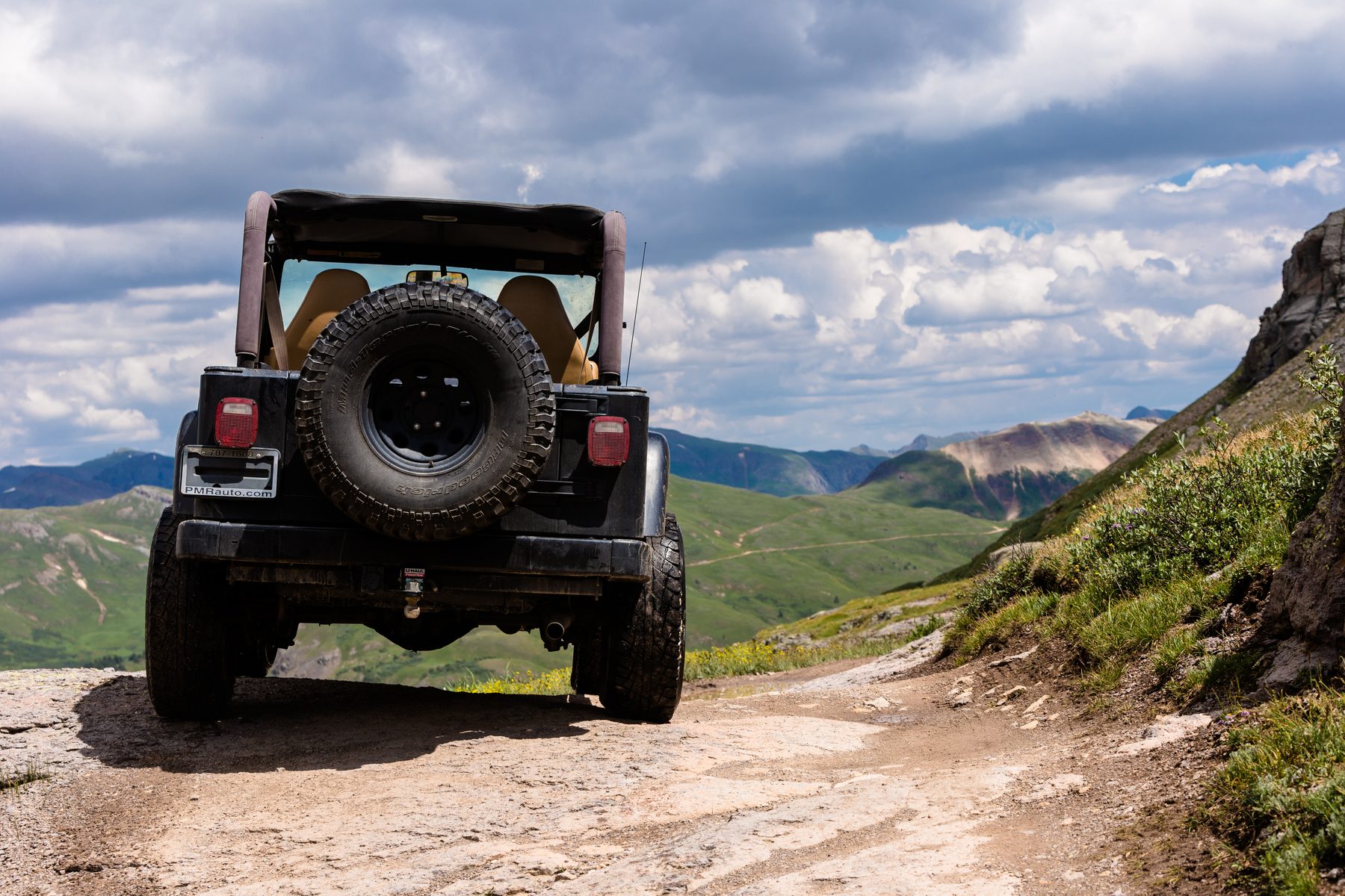 The back of a Jeep on a rough shelf road climbing into the high country