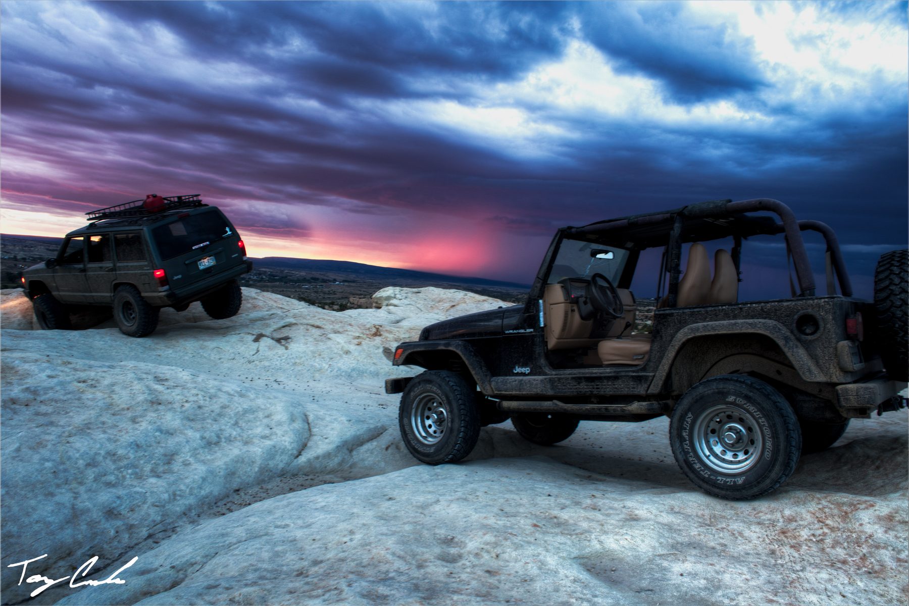 Two Jeeps parked on pale slickrock as the last colour leaves the sky