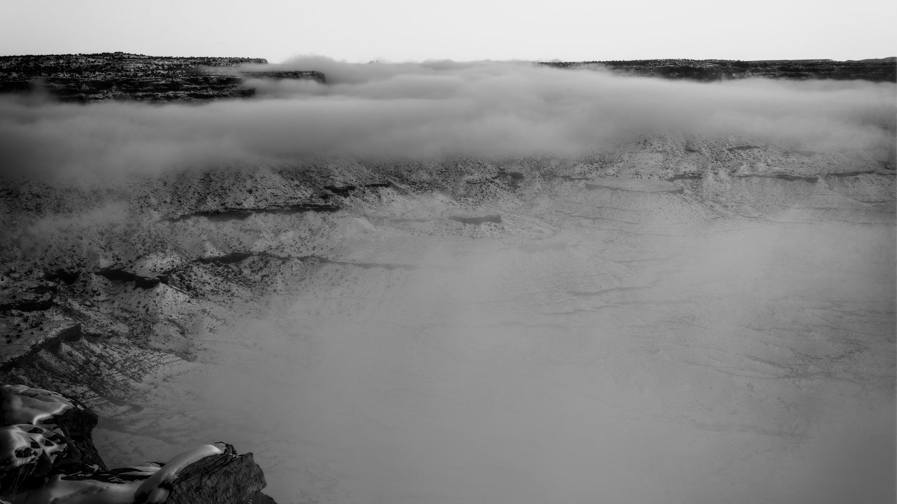 A black and white study of a cloud inversion filling a deep canyon
