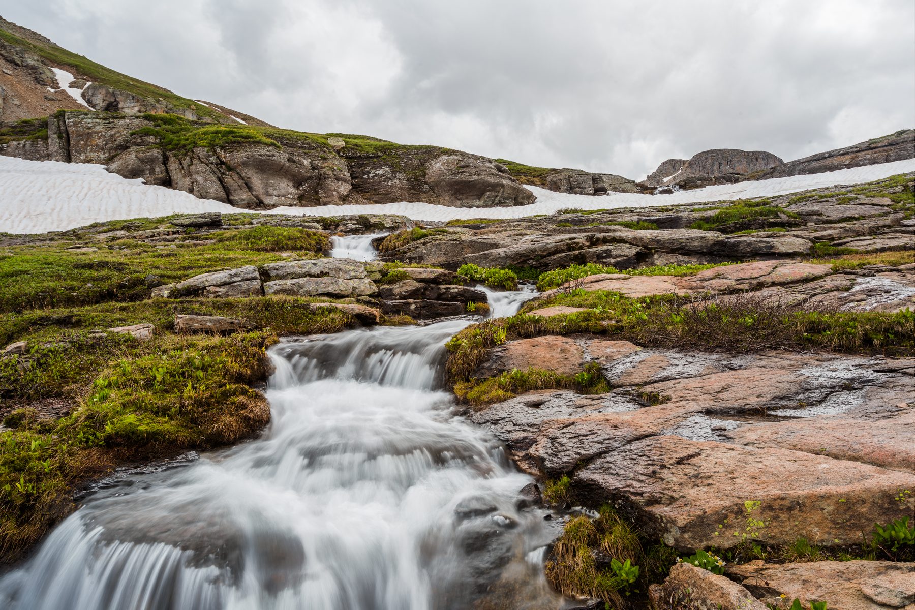 A small cascade running over rock slabs through alpine tundra
