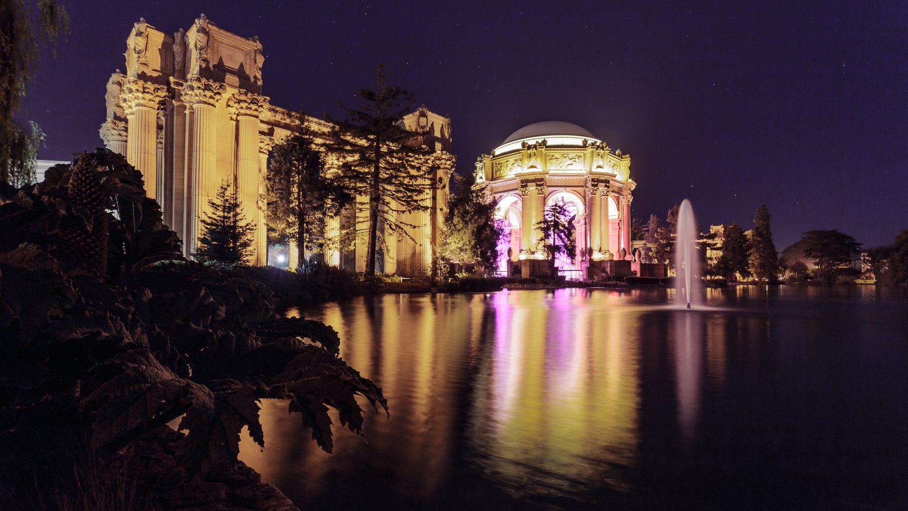 The Palace of Fine Arts lit at night and mirrored in its lagoon