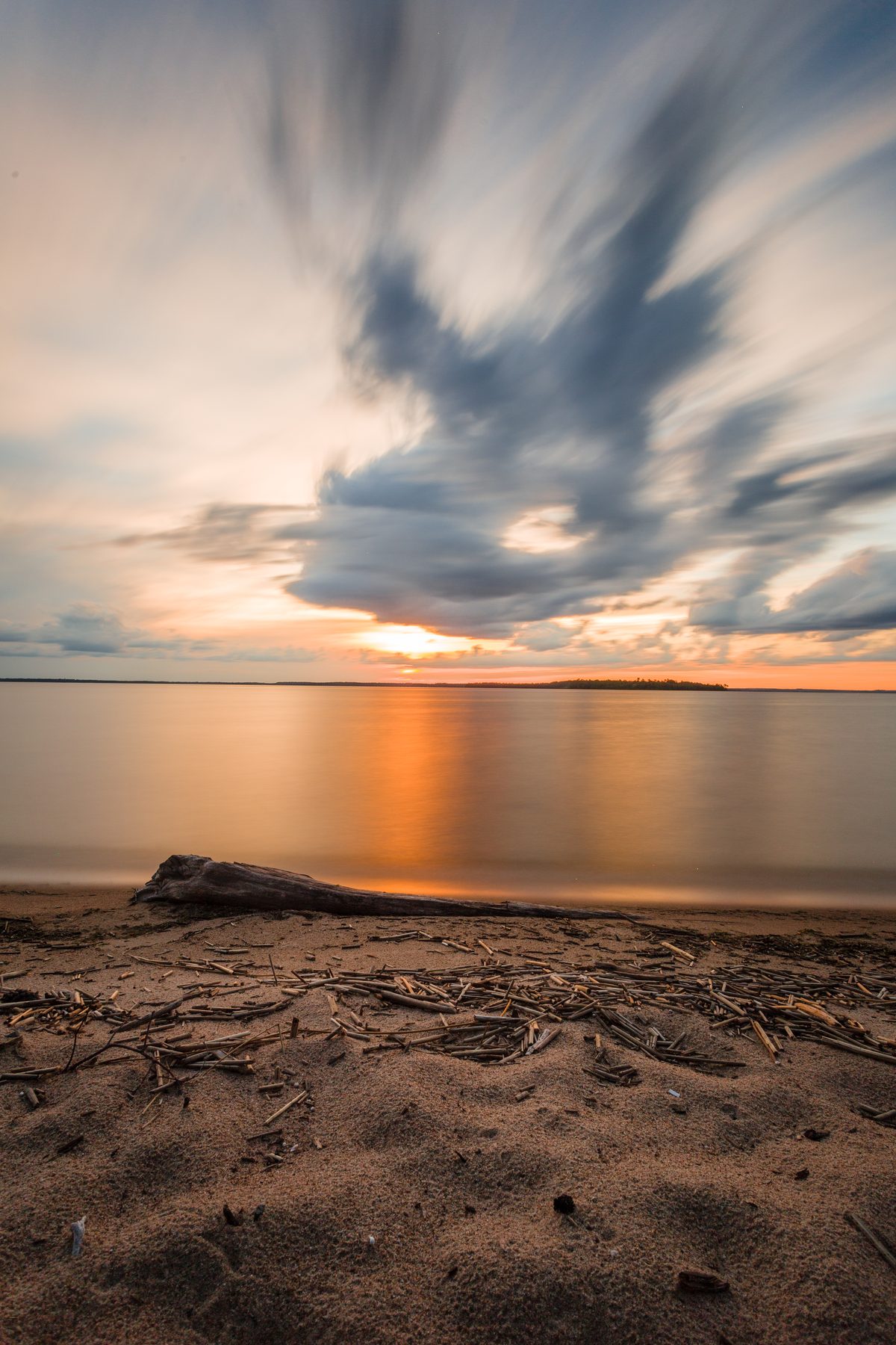 Evening light over a wide beach, cloud drawn into streaks by a long exposure